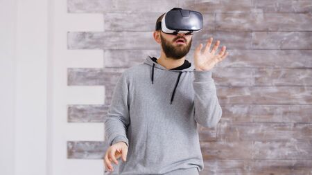Caucasian home designer using virtual reality goggles inside of an empty apartment to decorate it in...