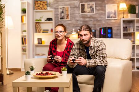 Gamers couple playing video games on the TV with wireless controllers in hands.の写真素材