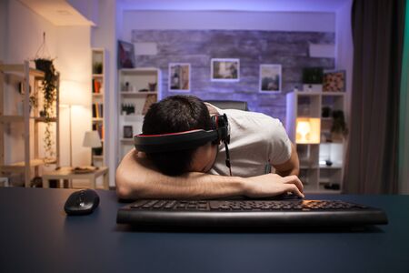 Pov of young man keeping his head on the office after losing and shooter game on stream.の写真素材