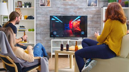 Cheerful caucasian friends playing video games on big tv in living room.