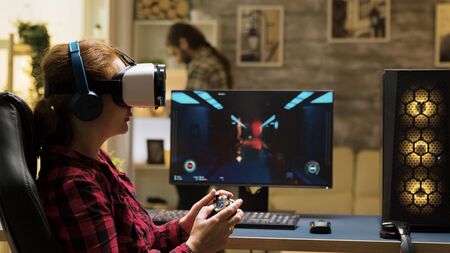 Professional female gamer using vr headset and wireless controller to play computer games. Man...
