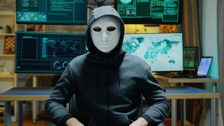 Dangerous hacker hiding his identity wearing a white mask while using augmented reality to steal confidential data.の写真素材