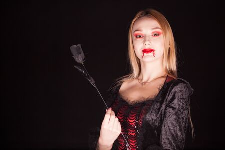 Caucasian vampire woman with bloody lips over black background. Halloween costume.の写真素材