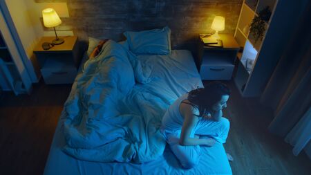 Young woman suffering from insomnia while her husband is sleeping. Room with moon light.の写真素材