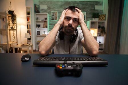 Pov of devastated professional shooter gamer after a big game over on online competition using wireless joystick.の写真素材