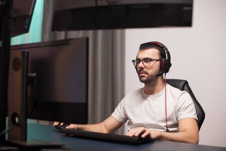 Portrait of professional gamer playing shooter games on powerful computer with multiple monitors.の写真素材
