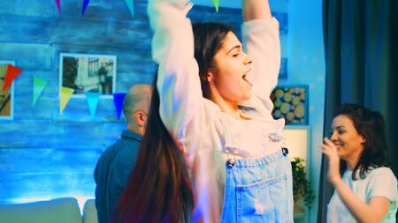 Attractive young woman dancing at the party with her friends. Group of people partying. Handheld slow motion shotの写真素材