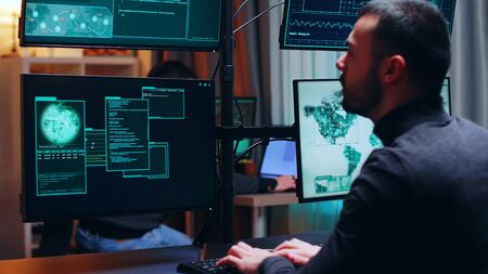 Dangerous hacker watching multiple monitors while working. Cyber criminal.の写真素材