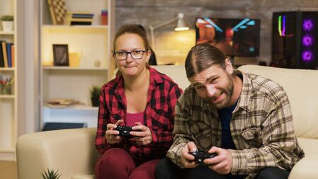 Woman yelling at her boyfriend after losing at video games sitting on couch. Man and woman playing...
