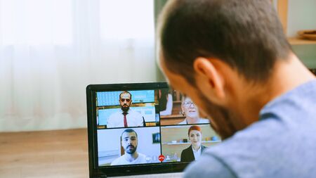 Zoom out shot of man on a video call with his work team during covid-19 lockdown.の写真素材