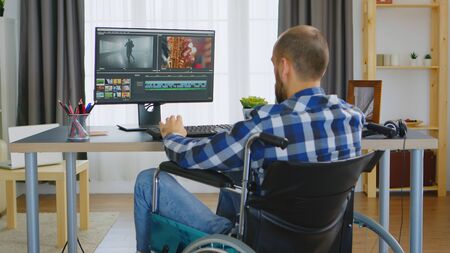 Content creator with walking disability in wheelchair working on one of his project.の写真素材