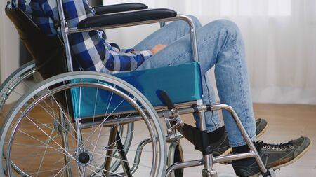 Invalid thoughtful man in wheelchair looking lost on window.の写真素材