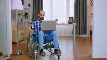Handicapped freelancer in wheelchair working on laptop.