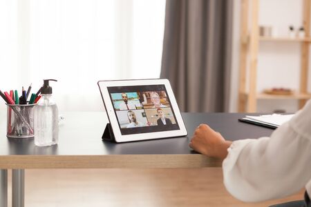 Woma in a video conference with collegues using tablet computer.