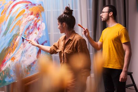 Creative couple painting on canvas in art studio. Modern artwork paint on canvas, creative, contemporary and successful fine art artist drawing masterpieceの写真素材