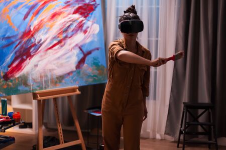 Painter using virtual reality headset in art studio creating a masterpiece. Modern artwork paint on canvas, creative, contemporary and successful fine art artist drawing masterpieceの写真素材