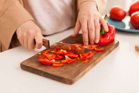 Close up of hand slicing pepper on cutting board in kitchen.の写真素材