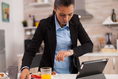Woman hurrying up to finish breakfast while shes late at the meeting. Young freelancer working around the clock to meet her goals, stressful way of life, hurry, late for work, always on the runの写真素材