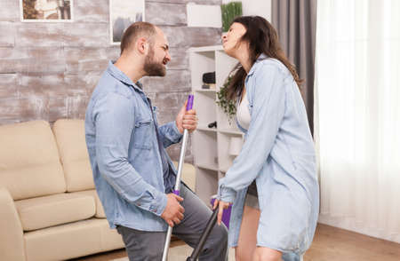 Couple full of happiness singing and dancing while doing housekeeping.の写真素材