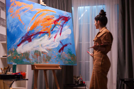 Happy artist in art studio after creating a masterpiece on large canvas. Modern artwork paint on canvas, creative, contemporary and successful fine art artist drawing masterpieceの写真素材