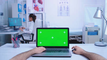 Pov shot of physician using laptop with chroma key in hospital cabinet and doctor looking at x-ray image.の写真素材