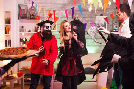 Young woman dressed up like a witch for halloween arriving with pizza at the party.の写真素材
