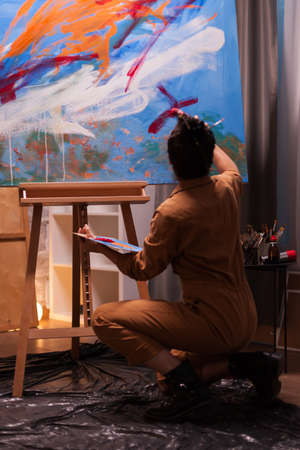 Back view of artist in art studio working on impressionism painting. Modern artwork paint on canvas, creative, contemporary and successful fine art artist drawing masterpieceの写真素材
