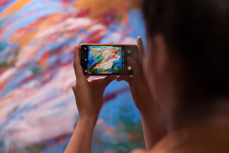 Young artist taking photo of masterpiece painting in art workshop. Modern artwork paint on canvas, creative, contemporary and successful fine art artist drawing masterpieceの写真素材