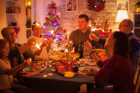 Big happy family celebrating christmas with delicious food and sparkles.の写真素材