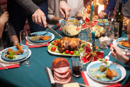 Close up of man slicing roasted chicken at christmas celebration for his family.の写真素材
