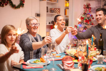 Senior woman and her daughter laughing at christmas celebration and holding hand fireworks.の写真素材