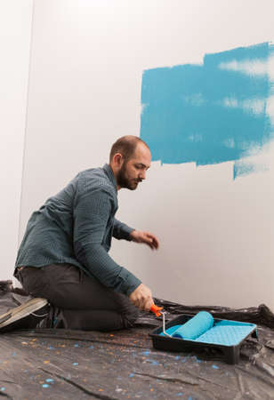 Husband renovating apartment living room using blue color. Home during renovation, decoration and...