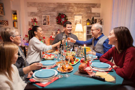 Happy senior man clinking a glass of wine with his daughter at christmas family dinner.の写真素材