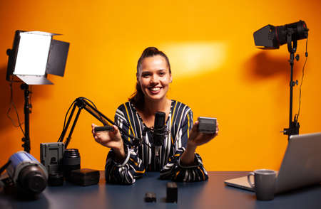 Famous vlogger smiling while recording video about professional accumulators. Presenting review studio portable testing modern batteries li-lion accessory device modern lighting technology.の写真素材