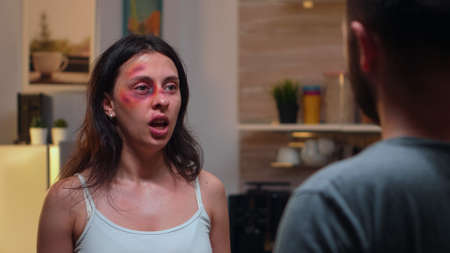 Alcoholic partener raising hand to wife. Abused terrified beaten wife covered in bruises suffering injury from drunk violent brutal aggressive husband screaming and fighting.の写真素材