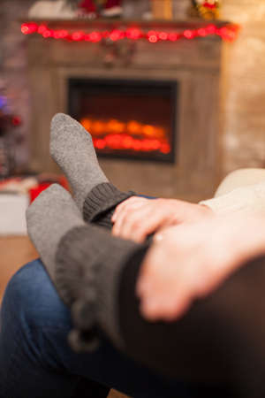 Boyfriend holding his hands on his girlfriend feet celebrating christmas in living room.の写真素材