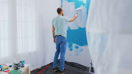 Dipping roller brush in paint. Home renovation, Handyman renovating. Apartment redecoration and home...
