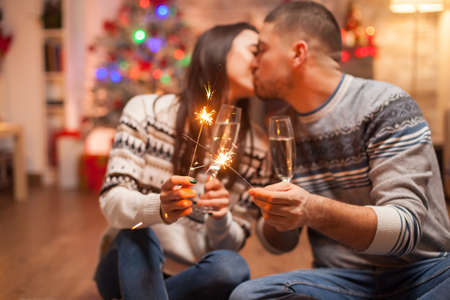 Caucasian couple kissing while holding fireworks on christmas day.の写真素材