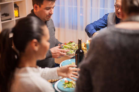 Cheerful man at christmas family dinner with a bowl with delicious salad.の写真素材