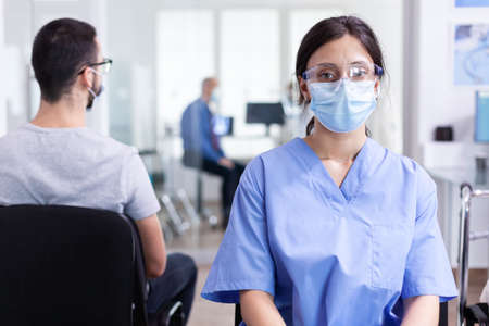 Medical assistant with visor and face mask against coronavirus during global pandemic. Doctor...