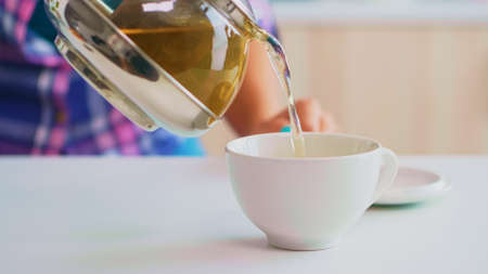 Green tea flowing from teapot in slow motion. Close up of tea from the kettle slowly pour into...