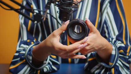 Close up of content creator making a review for new camera lens in professional studio set. New media star influencer on social media talking video photo equipment for online internet web showの写真素材