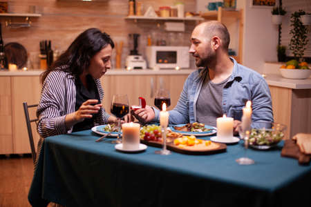 Woman surprised by marriage proposal from husband during romantic dinner. Kitchen during romantic dinner. Happy caucasian woman smiling being speechlessの写真素材