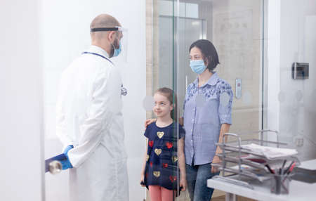 Pediatrician wearing face mask against coronavirus during consultation of child. Physician, specialist in medicine with protection mask providing health services, consultation.の写真素材