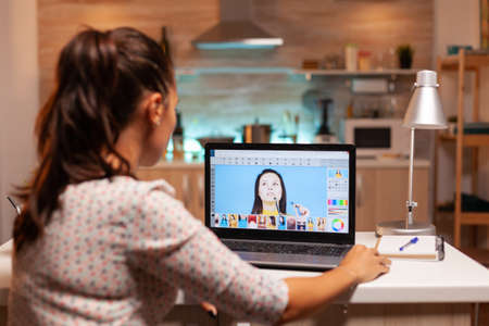 Professional photographer working on photos from home office during night time. Content creator doing portrait retouching using performance laptop, artist, occupation, screen, graphicの写真素材
