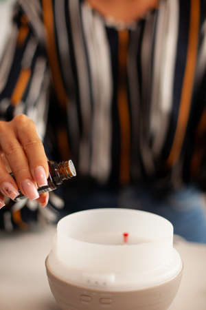 Pouring essential oils into diffuser for aromatherapy. Aroma health essence, welness home spa fragrance tranquil theraphy, therapeutic steam, mental health treatmentの写真素材