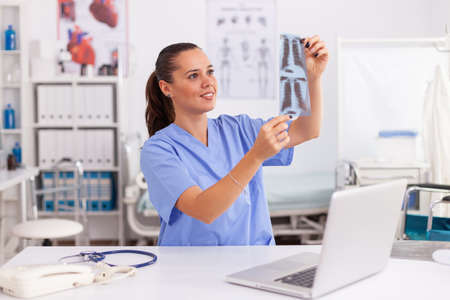 Medical nurse holding patient radiography in hospital office. Radiologist in medical uniform holding and looking at x-ray, examination, bone, practitioner, analyze, diagnosis.の写真素材