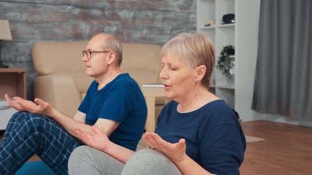 Retired senior couple doing breathing exercises on yoga mat in living room. Old person healthy and active lifestyle exercise and workout at home, elderly training and fitnessの写真素材