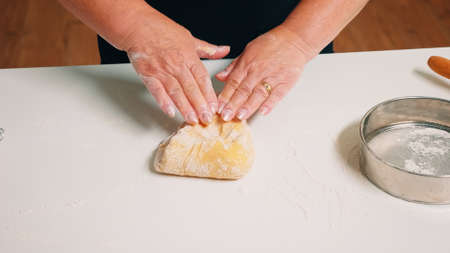 Closeup shot of hands of senior bakery kneading dough.