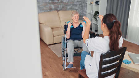 Invalid old woman in wheelchair doing rehab training with support from doctor. Disabled handicapped...